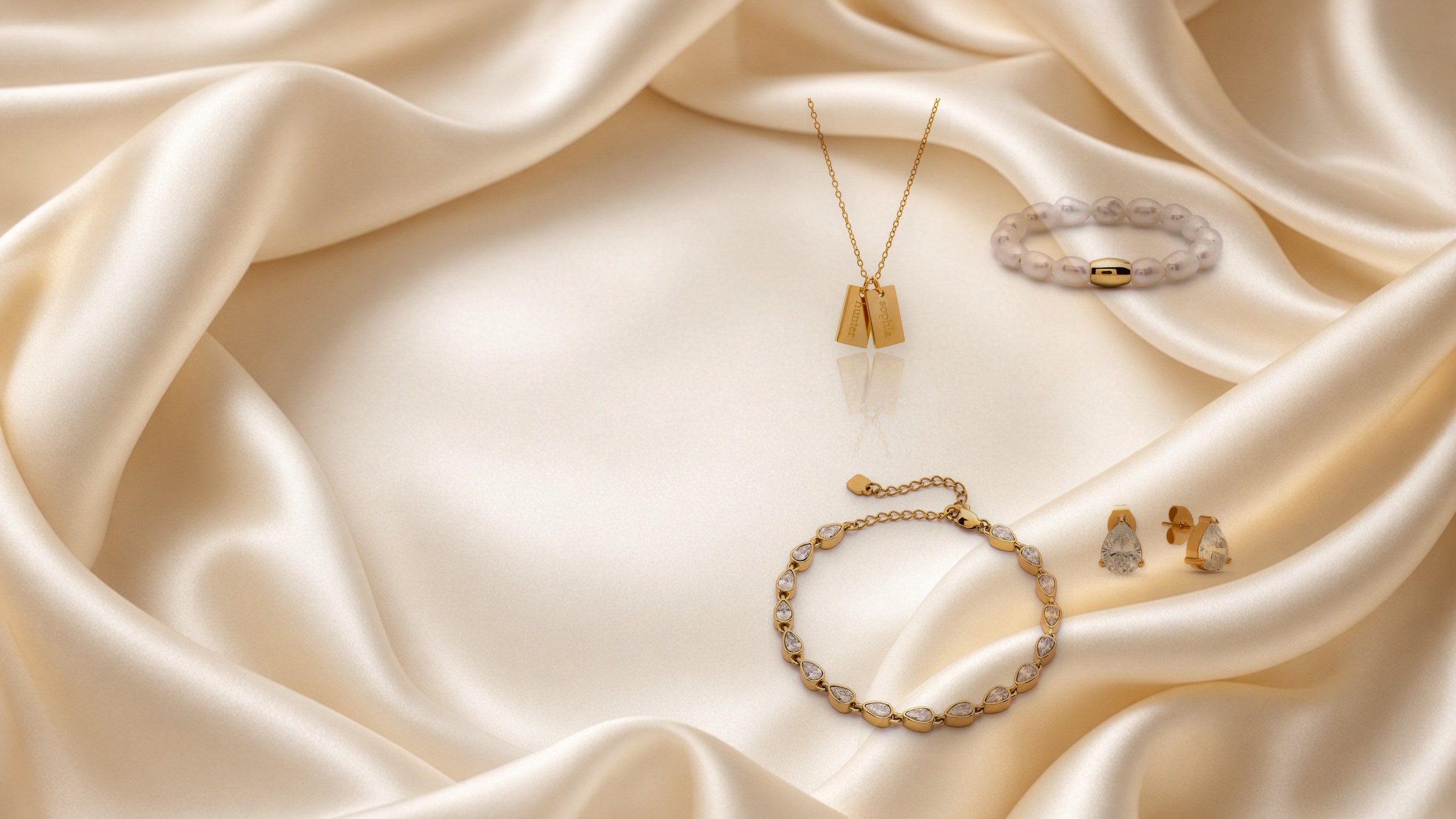 Gold necklace, pearl ring, tennis bracelet and teardrop studs on ivory silk